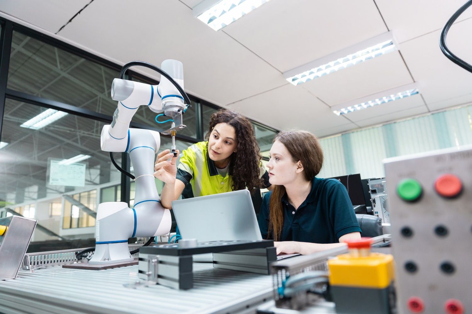 Zwei engagierte junge Ingenieurstudentinnen arbeiten im Team und befassen sich mithilfe eines Roboterarms mit der Robotertechnologie.
