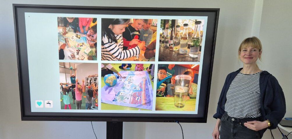 Eine Frau steht vor einem Fernseher und zeigt 6x Fotos in einer Kollage, in der Kollage sieht man Kinder die spielen, sich mit dem Thema Wasser auseinandersetzen