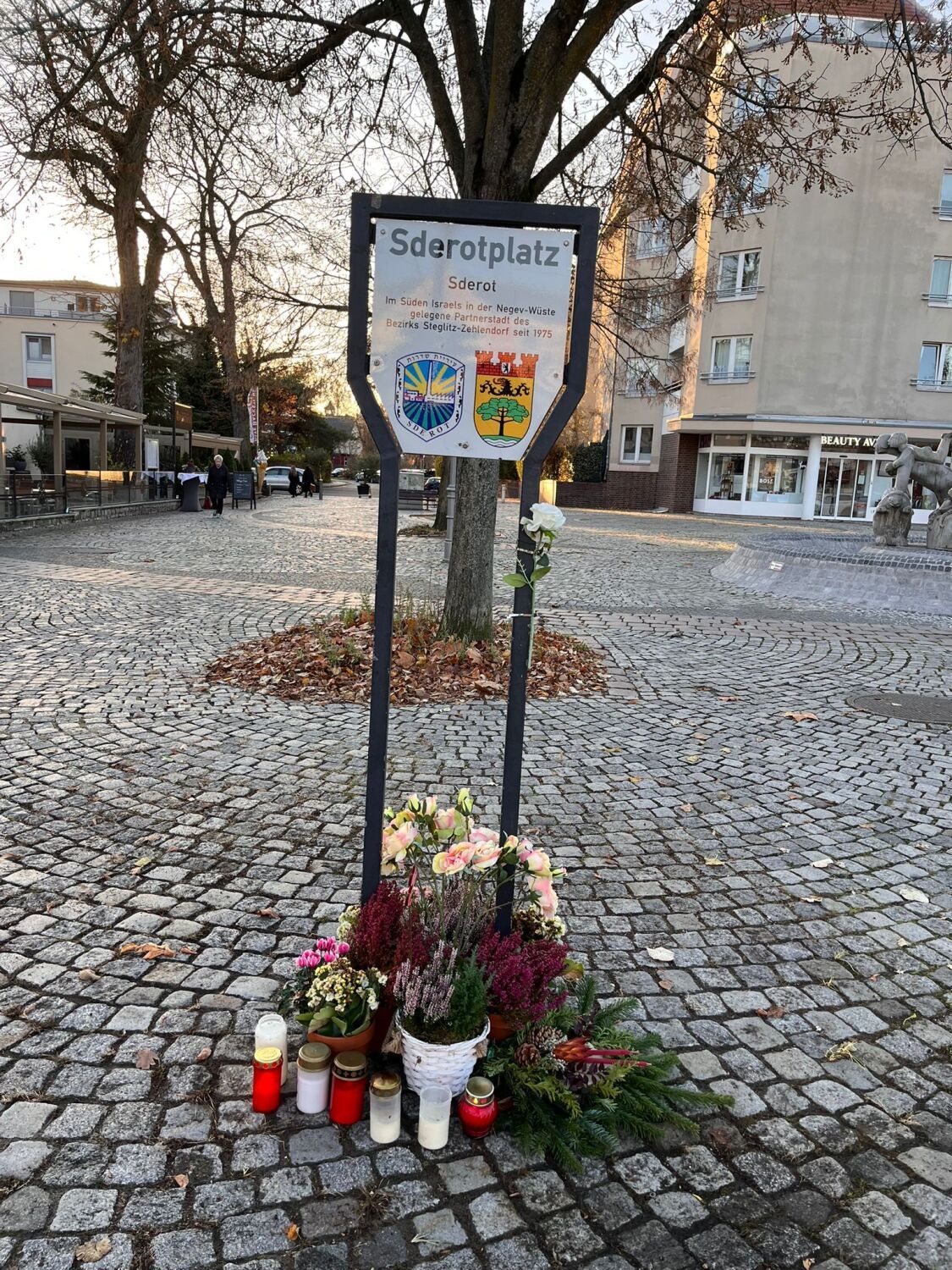 Danach: Neues Ensemble aus Blumen, Kerzen und Tannengrün unter dem Schild des Sderotplatzes