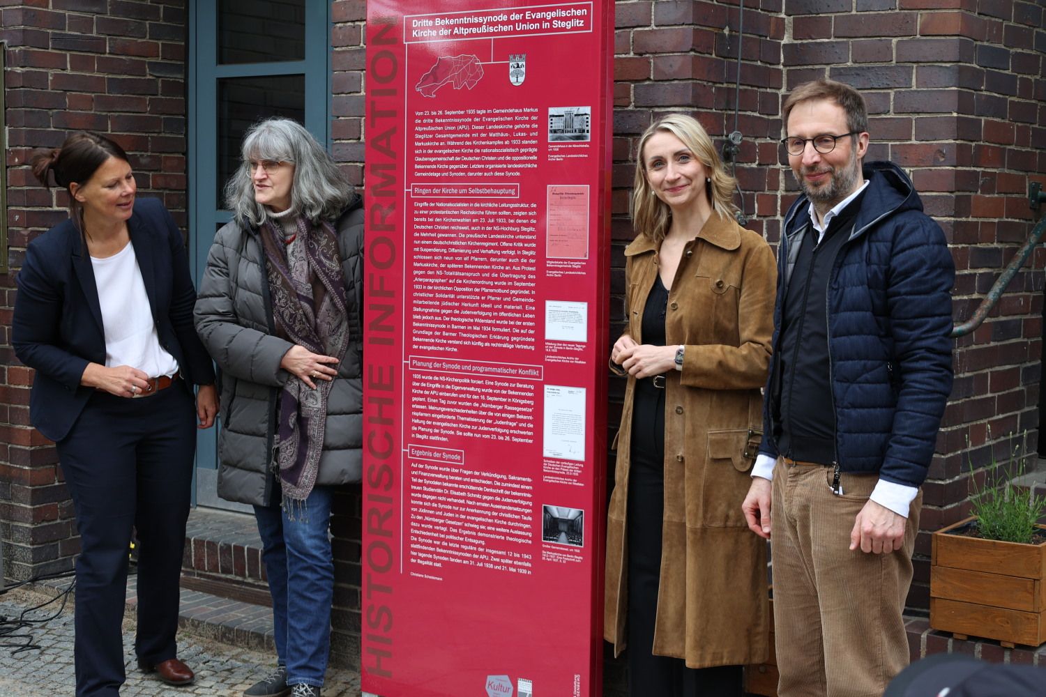 7. Mai 2026: Die Stele ist enthüllt - v.l.n.r.: Superintendentin Christa Olearius (ev. Kirchenkreis Steglitz), Dr. Christine Scheidemann (Historikerin und Autorin des Stelentextes), Bezirksstadträtin Malgorzata Sijbrandij, Pfarrer Sven Grebenstein (Markuskirchengemeinde)
