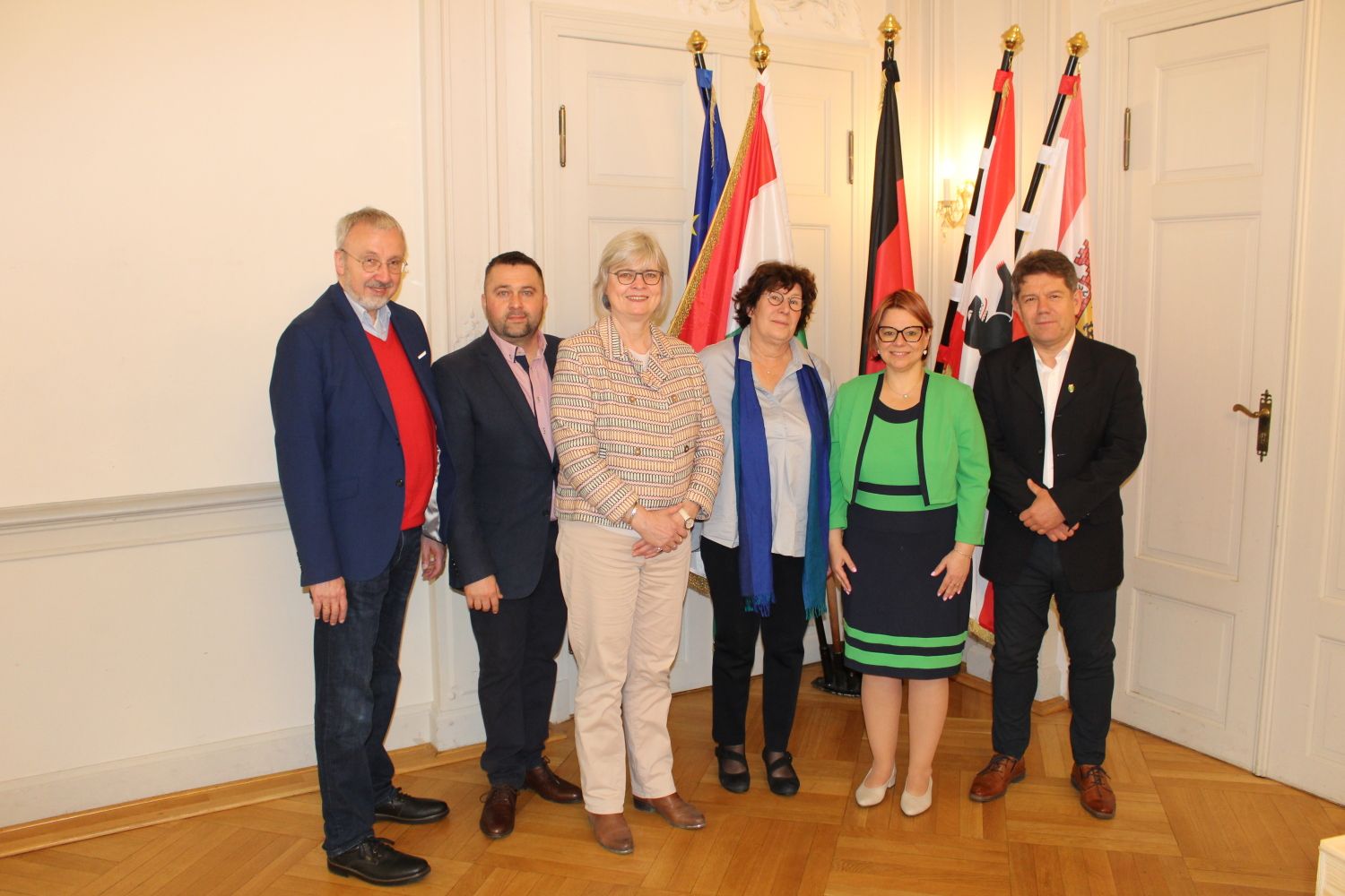24. Mai 2025: Gruppenbild mit Fahnen - die ungarische Besuchsdelegation unter der Leitung von stellv. Bezirksbürgermeisterin Kinisch (2.v.r.); Bezirksbürgermeisterin Schellenberg (3.v.r.) und stellv. Bezirksbürgermeisterin Richter-Kotowski (3.v.l.) aus Steglitz-Zehlendorf; BVV-Vorsteher René Rögner-Francke (ganz links)