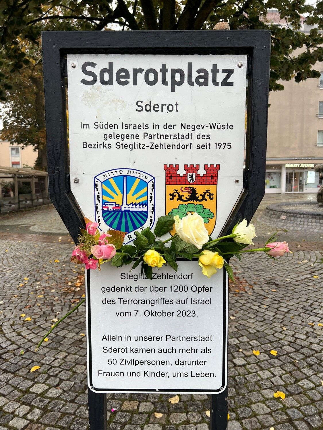 Platzschild des Sderotplatzes mit neu angebrachtem Zusatzschild, das an den 7. Oktober 2023 erinnert