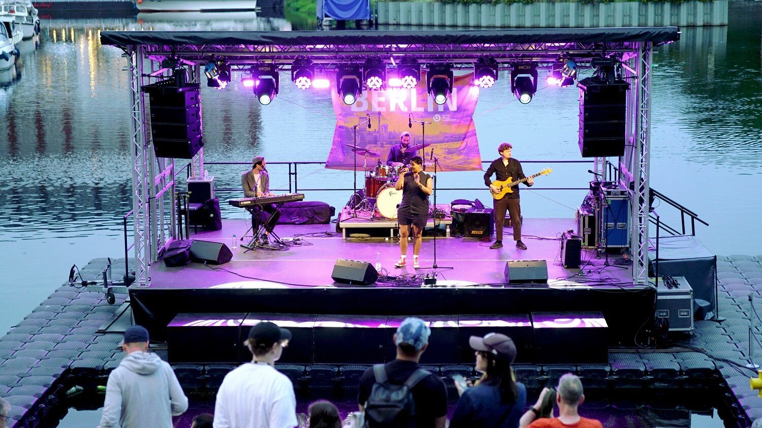schwimmende Bühne im lila Licht mit einer Band
