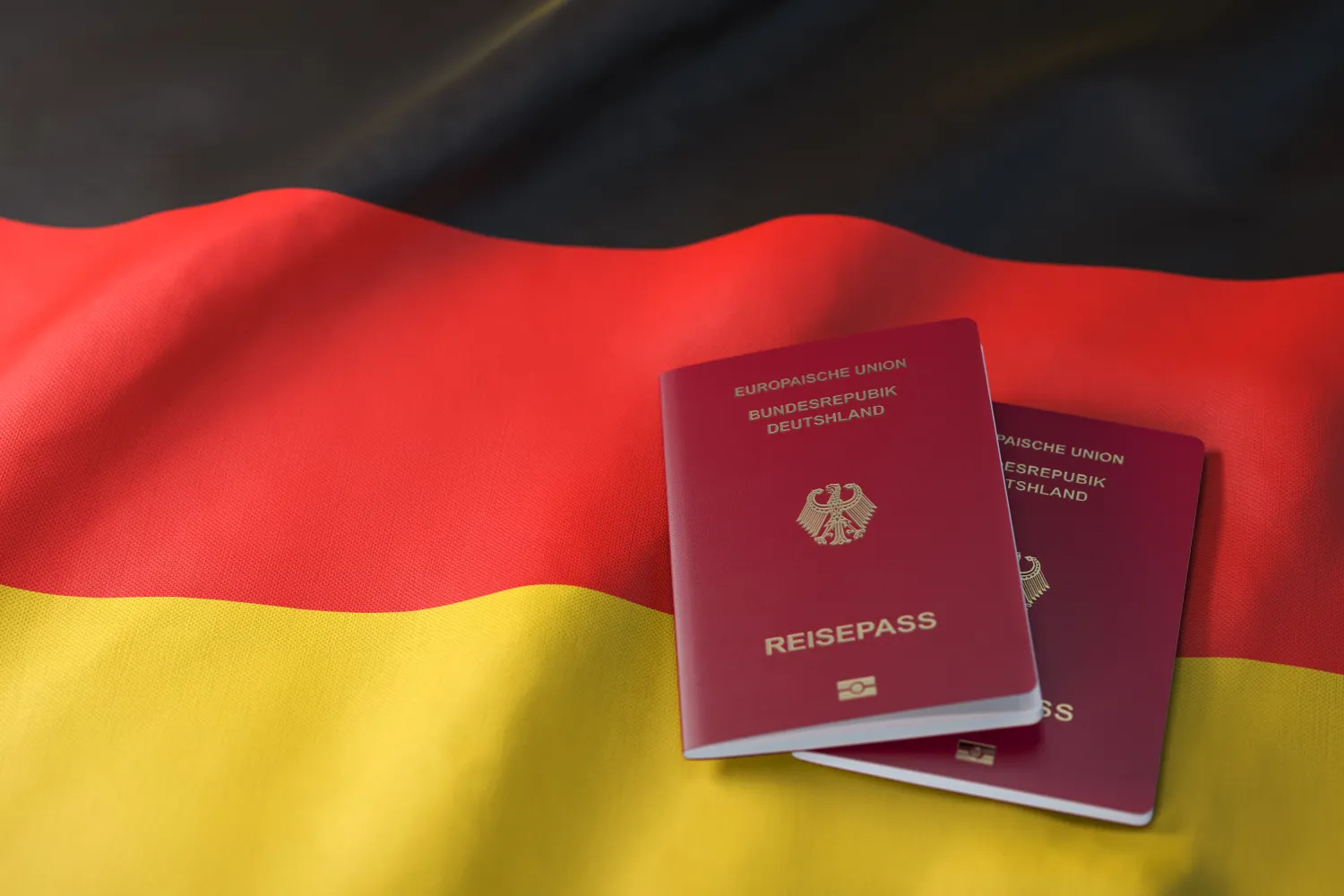 Zwei deutsche Reisepässe liegen auf der deutschen Flagge mit den Farben schwarz-rot-gold