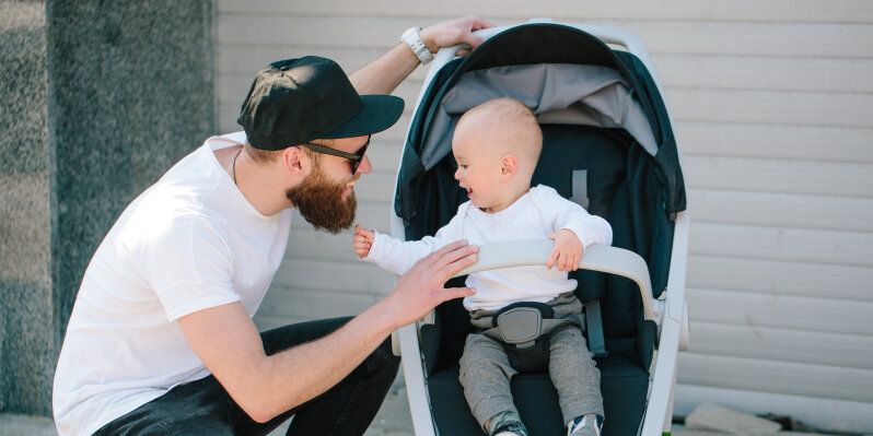 Vater mit einem Kinderwagen und ein Baby in den Straßen der Stadt zu Fuß