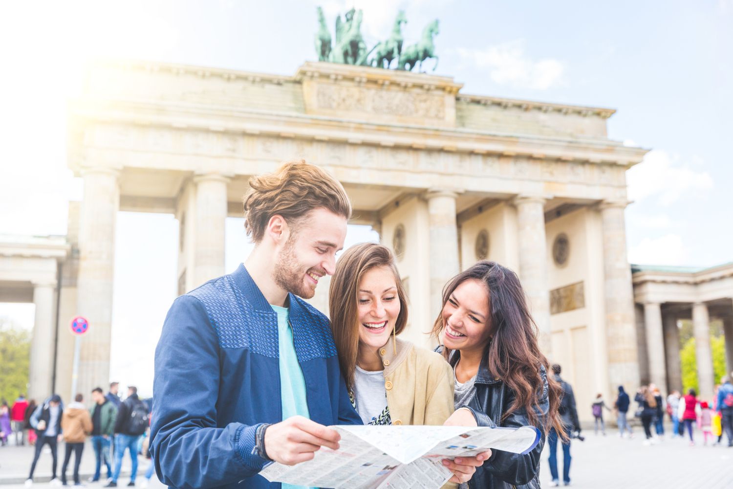 Eine Gruppe von Freunden schaut vor dem Brandenburger Tor auf einen Stadtplan