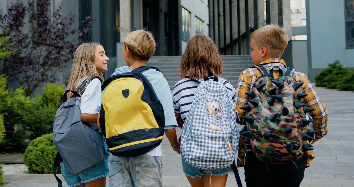 Vier Kinder mit Schulranzen auf dem Weg zur Schule