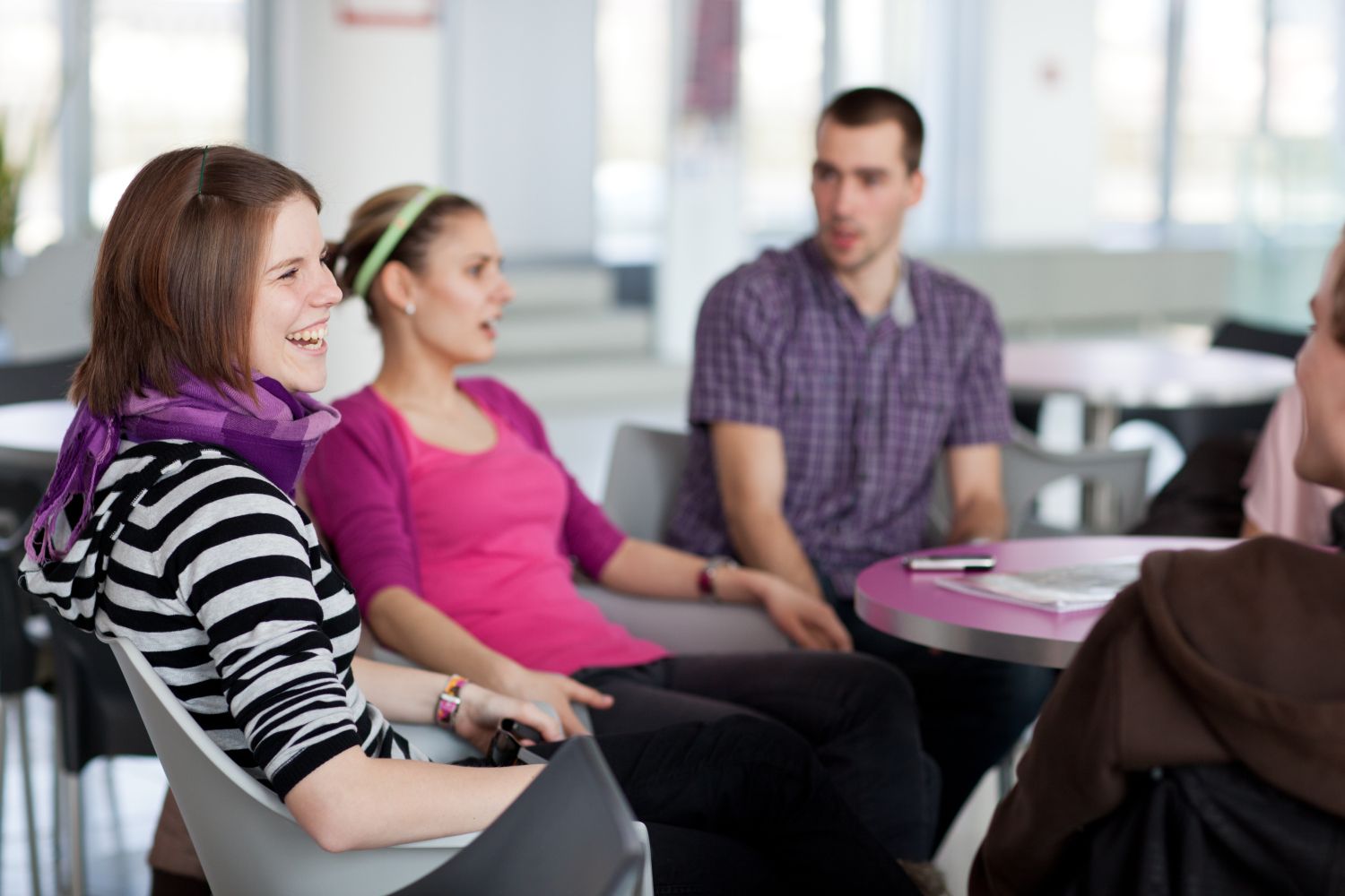 Gruppe junger lachender Studenten an einem Tisch