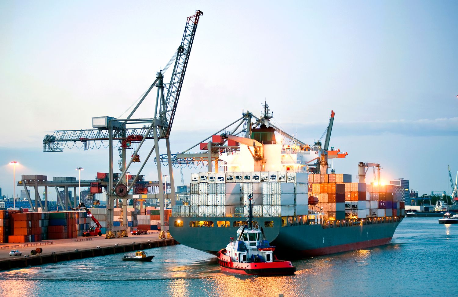Ein riesiges Containerschiff wird von Lotsen und Schleppern manövriert und rückwärts in Richtung Land gebracht.
