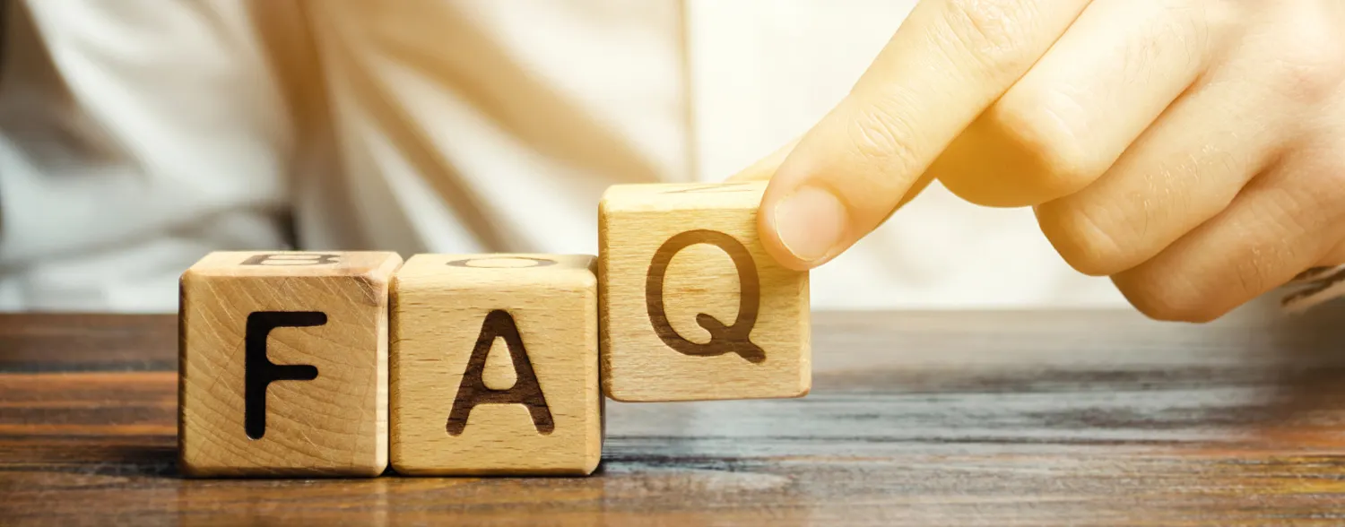 FAQ; drei nebeneinander liegende Würfel mit den Buchstaben F, A und Q. Der Würfel mit dem Q wird von einer Hand hochgehoben