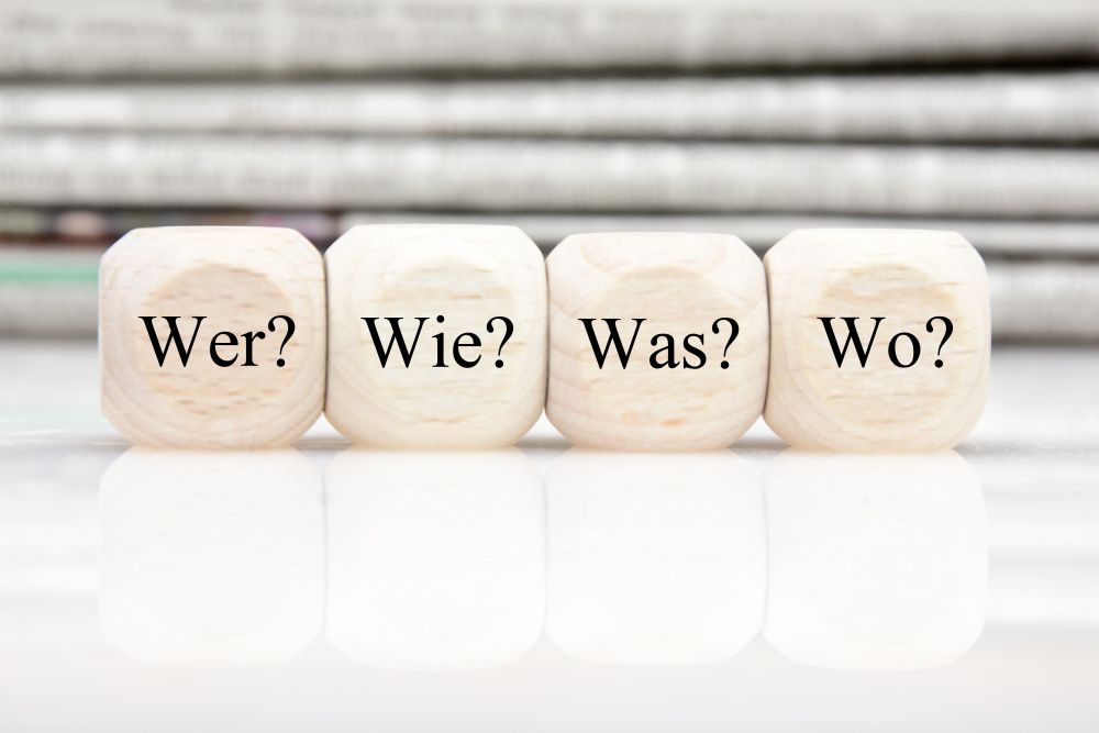 Vier Würfel mit den Fragen Wer? Wie? Was? Wo?
