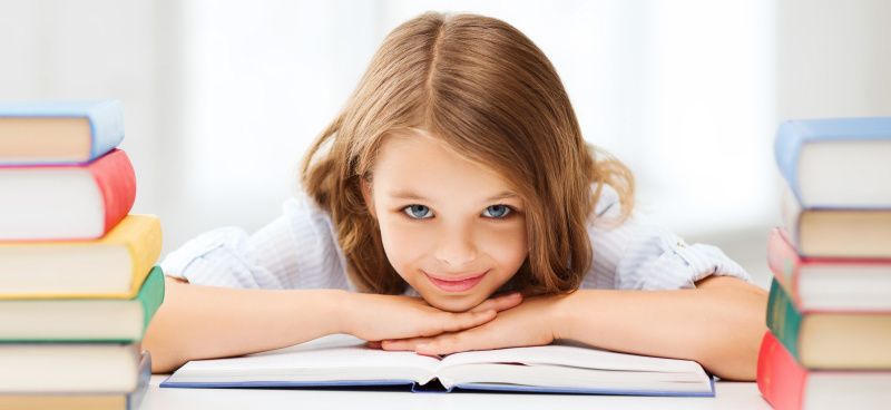 Mädchem liegt auf einem Stapel Büchern