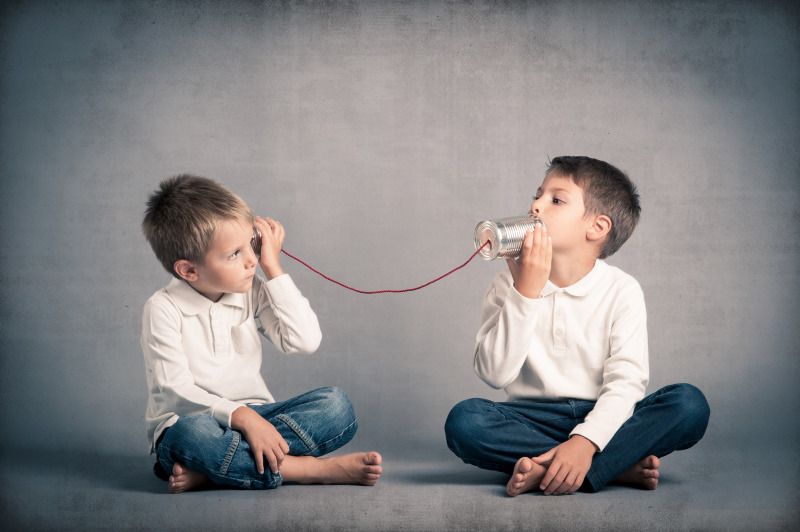 Zwei Brüder telefonieren, indem sie Blechbüchsen an ihre Ohren halten.
