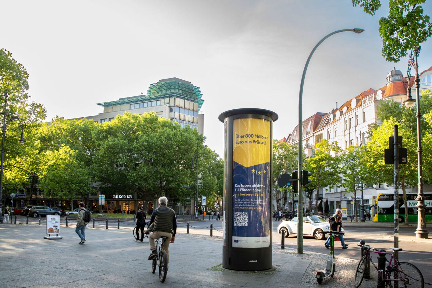 Eine Litfaßsäule mit Werbung in der Berliner Innenstadt, Bäume im Hintergrund