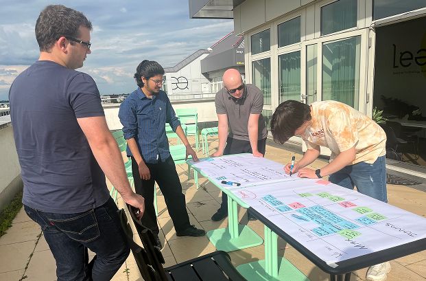 Terrasse mit vier Jugendlichen schreiben auf großformatiges Papier