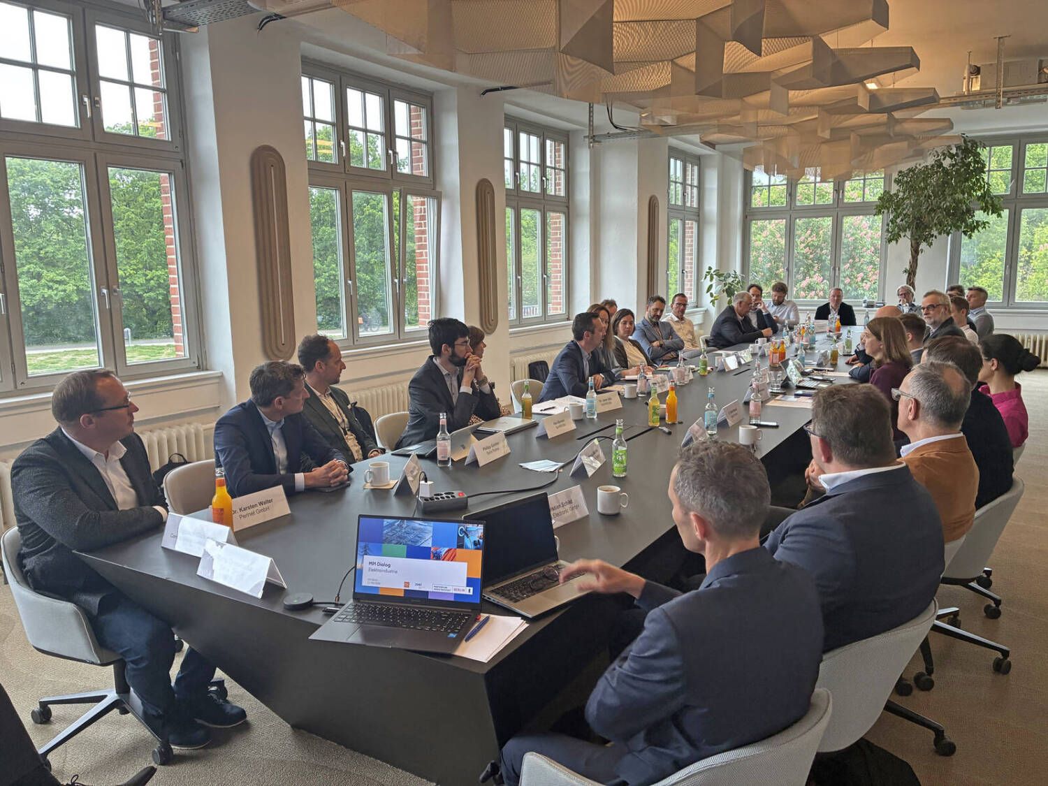 Ein Gruppe von Menschen in einem Konferenzraum sitzend an einem langen Konferenztisch