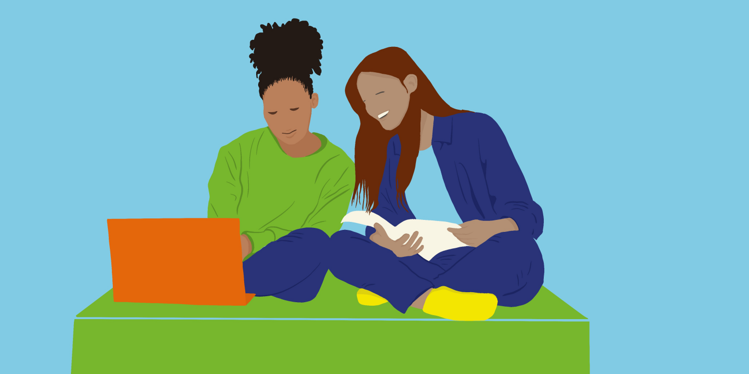 Zwei junge Frauen sitzen mit einem Laptop und einem Buch