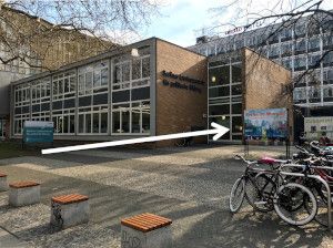 Vorplatz mit Eingangsbereich der Landeszentrale. Eingang der Landeszentrale mit einem weißen Pfeil markiert.