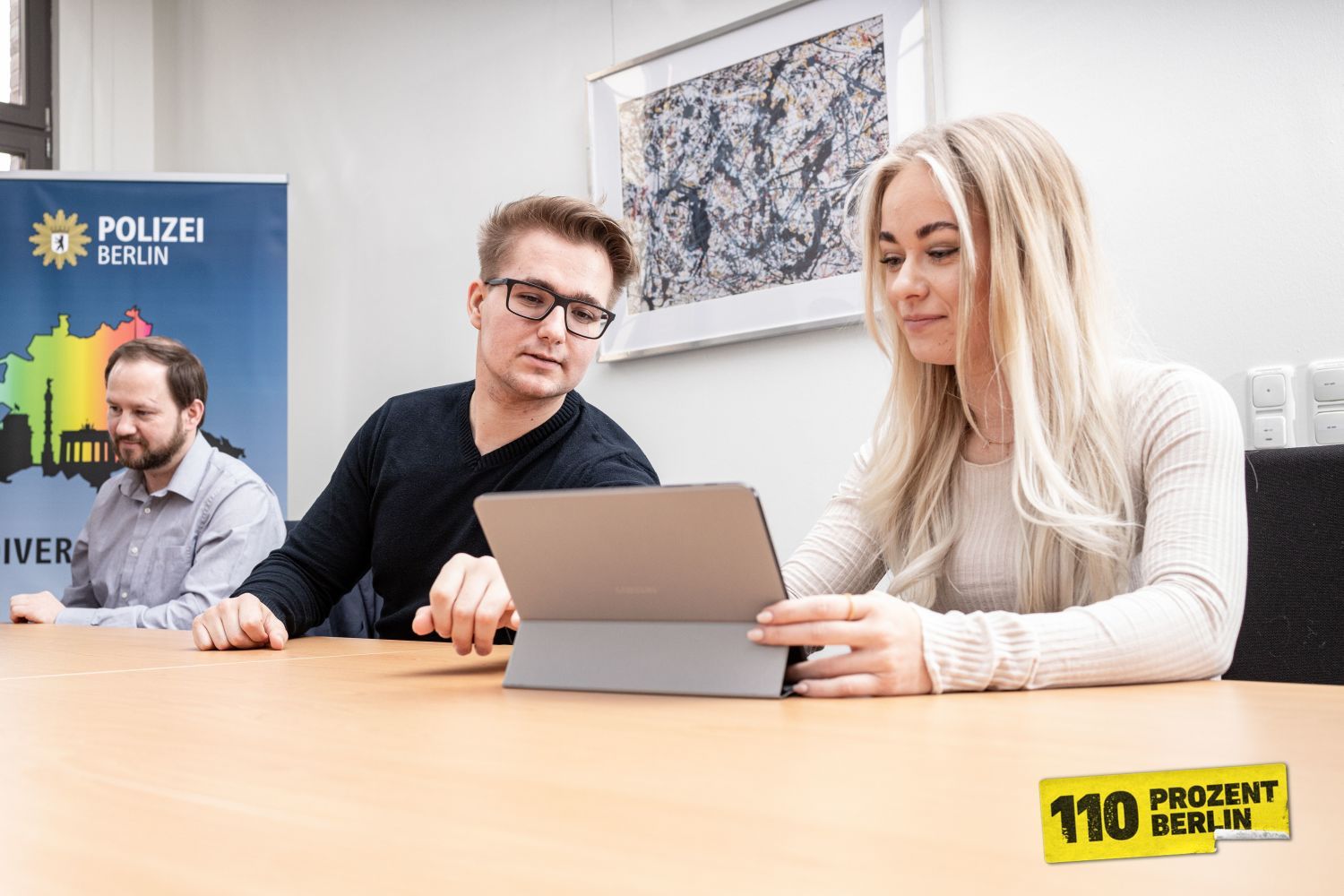 Drei Mitarbeiter im Büro, einer zeigt einer Kollegin etwas am Tablet