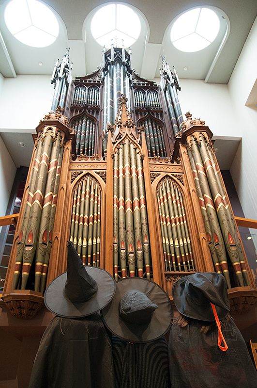 3 Kinder mit Zauberhüten schauen auf eine große Kirchenorgel