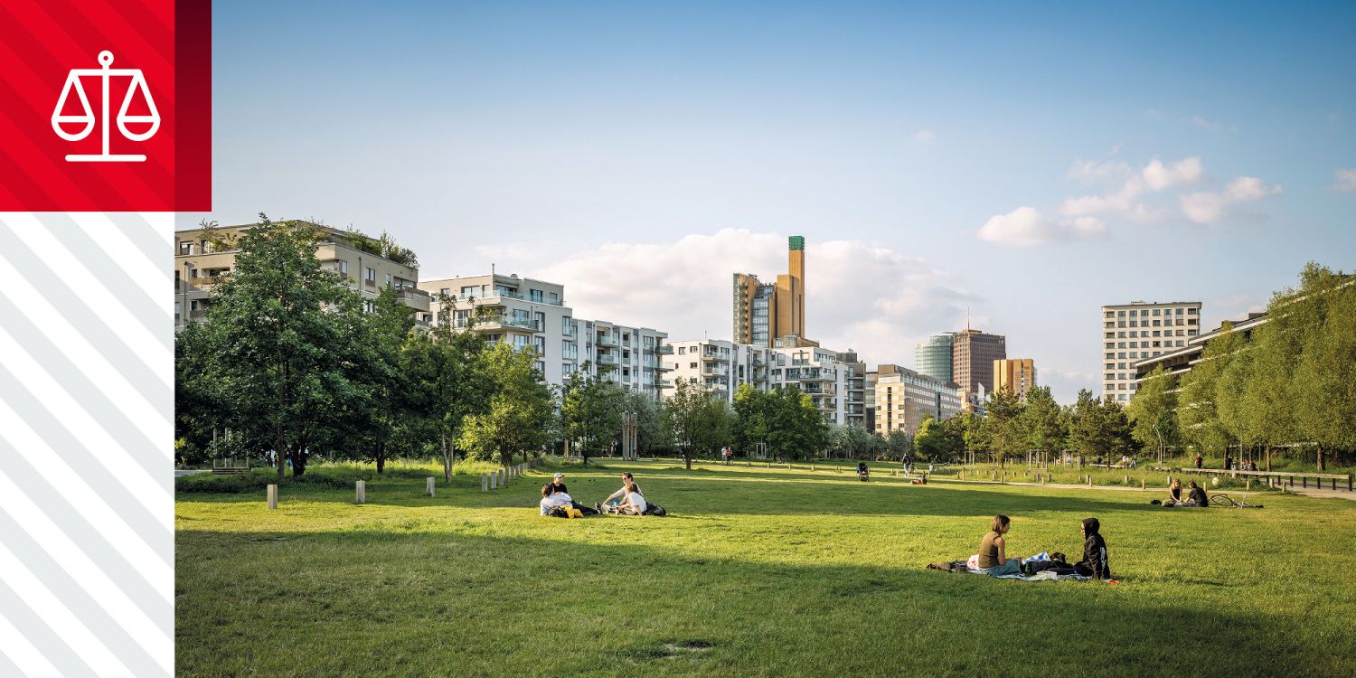 Wiese mit sitzenden Menschen, Bäumen und Gebäuden des Potsdamer Platz im Hintergrund.