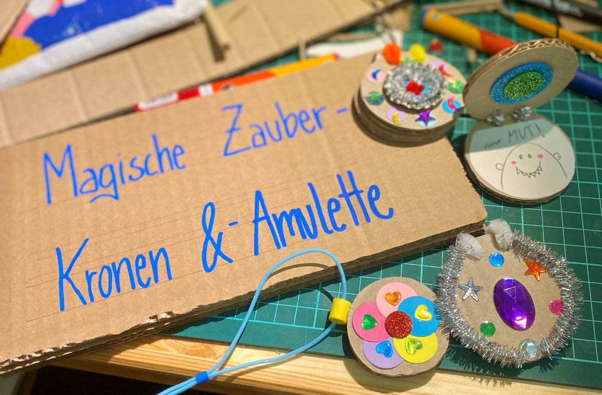 Workshop-Titel auf Kartonschild und verschiedene Glitzeramulette