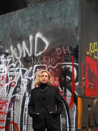 Eine Frau steht vor einer Graffitiwand