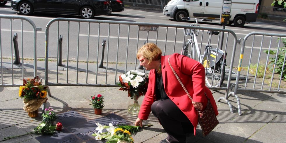 Eine Frau legt Blumen auf einen Gedenkstein nieder