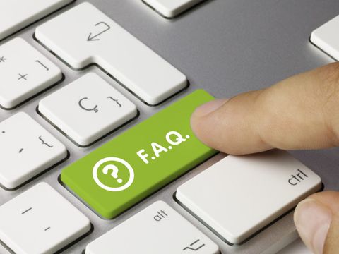Finger, der auf einer Computertastatur auf eine grüne Taste mit der Aufschrift FAQ klickt