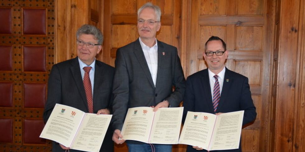 v.l.n.r.: Bürgermeister Dr. Haase, Vorsteher der Gemeindevertretung, Herr Damm, und Bezirksbürgermeister Igel zeigen das Memorandum of Understanding