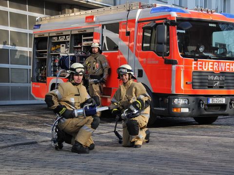Drei Feuerwehrleute vor einem Einsatzfahrzeug