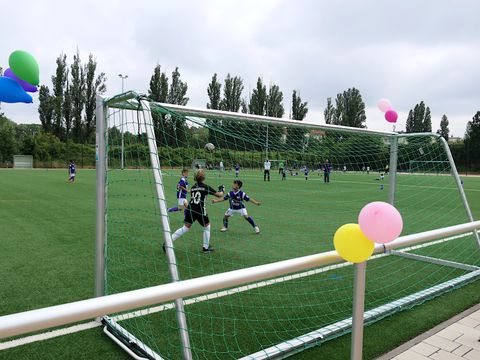 Blick auf Kinder beim Fußballspiel durch ein mit Ballons geschmücktes Tor