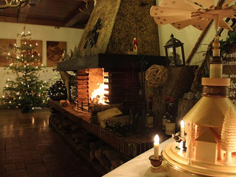 Weihnachtlich beleuchteter Raum mit Kamin, Weihnachtsbaum und Holz-Pyramide