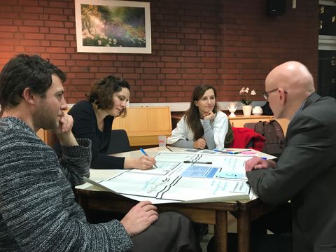 Vier Bürger_innen diskutieren an einem Tisch über die Empfehlungen des Bürger_innenrates