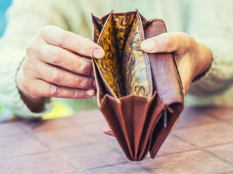 Ältere Frau hält Brieftasche ohne Geld in den Händen 