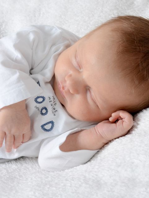 Ein Baby liegt schlafend auf einer Decke