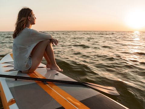 Young woman sitting on a stand up paddle board
