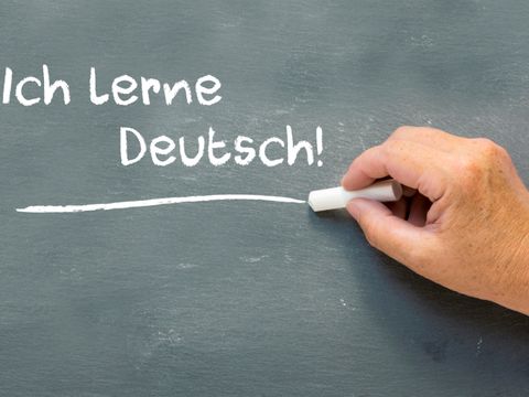 Hand auf einer Tafel mit dem deutschen Worte Ich Lerne Deutsch