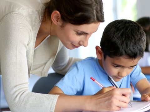 Lehrerin hilft kleinem Jungen bei den Hausaufgaben