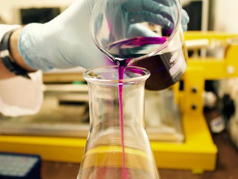 Eine chemische Flüssigkeit wird von einem Becherglas in ein Erlenmeyerkolben-Glas gefüllt.
