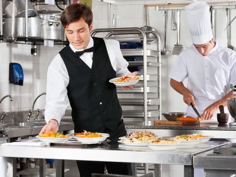 Kellner und Chefkoch beim Arbeiten in einer kommerziellen Küche