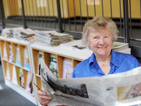 eine ältere Frau liest Zeitung