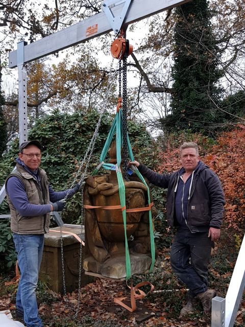 Bildvergrößerung: Steinrestaurator Pablo Ortiz und Steinmetz Johannes Victor heben die Schmettau-Gedächtnisurne mit einem Flaschenzug von ihrem Postament