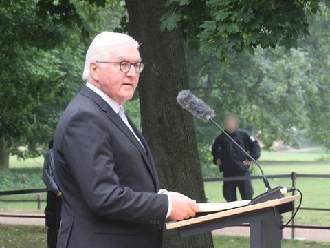 Bildvergrößerung: Ein älterer Mann steht am Mikrofon in einem Park.