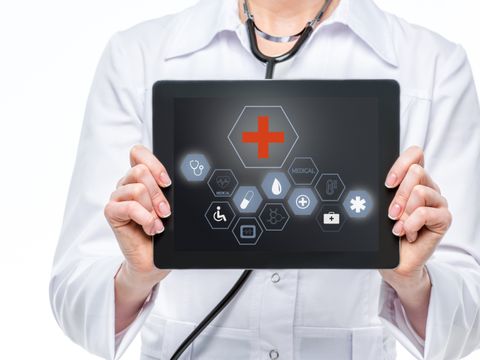 Ärztin hält Tablet mit medizinischen Symbolen darauf