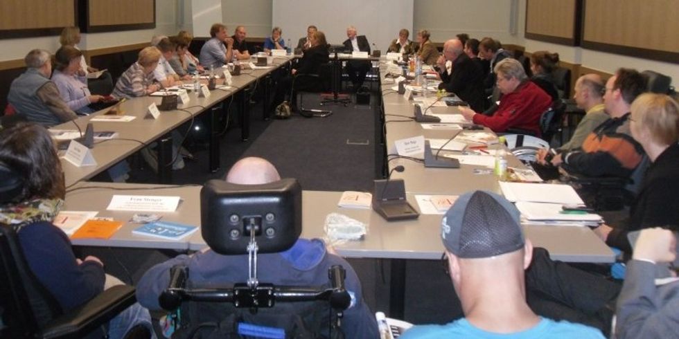 Mitglieder des Landesbeirats für Menschen mit Behinderungen diskutieren in einem Sitzungssaal