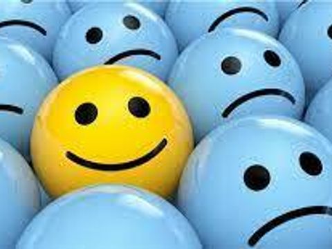 Ein optimistischer gelber Ball zwischen pessimistischen blauen Bällen