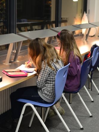 Bildvergrößerung: Zwei Schülerinnen sitzen am Arbeitsplatz und lernen