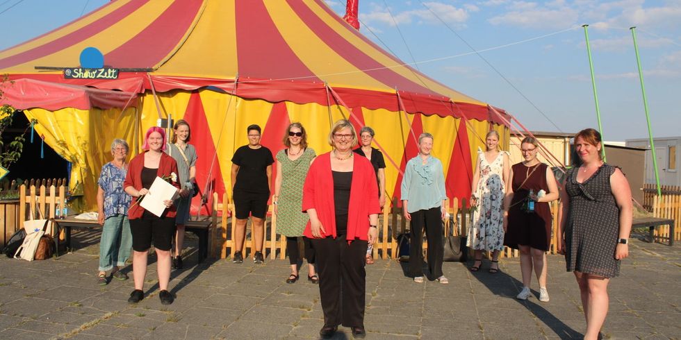 Eine Gruppe Frauen steht vor einem Zirkuszelt.