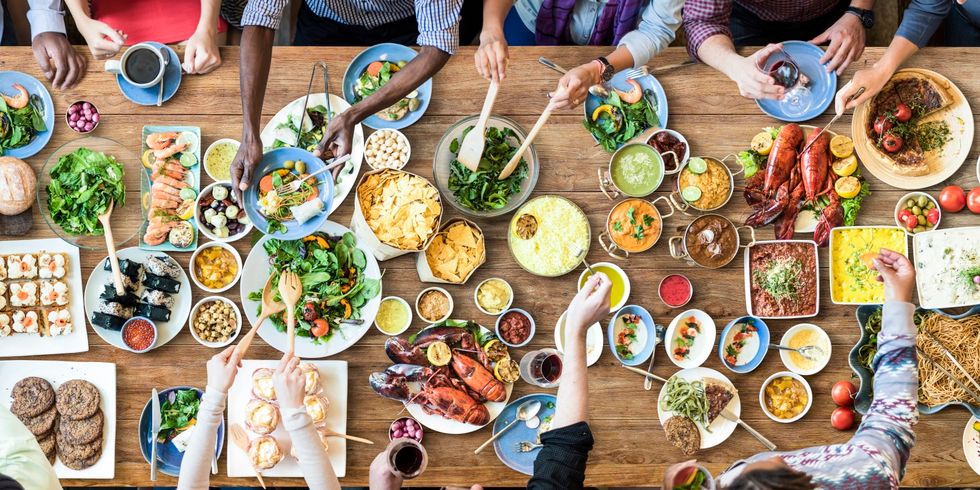 Multiethnische Leute essen am Tisch mit vielen Seisen verschiedener Länder